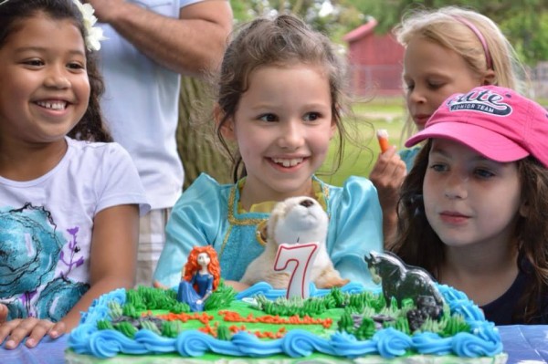 Katherine after blowing the candle out on her Disney Brave cake, while holding her WWF Wildlife Adoption river otter.