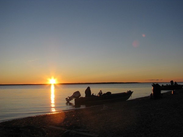 The sun sets for the first time of the summer of the shores of Darnley Bay near Paulatuk, NWT, while a hunter returns to his camp after fishing. ©Dan Slavik/ WWF-Canada
