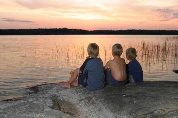 Three boys on lake shore looking at sunset. © Jupiter Images