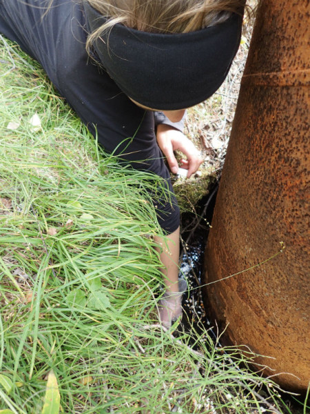 Collecting samples from a 30+ year old pipe protruding from the ground. © Aimee Guile 