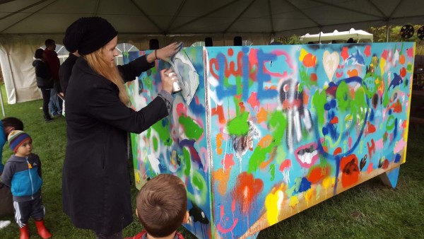House of PainT workshop facilitator paints a dolphin on a mural as part of their Ottawa Wave Makers project.