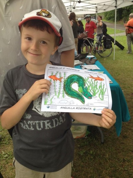 A young participant holds up a coloured drawing of the Ottawa River eel.