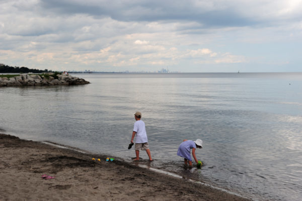 With the skyline of Toronto on the horizon, children play in the water on the shores of Lake Ontario, Ontario, Canada.