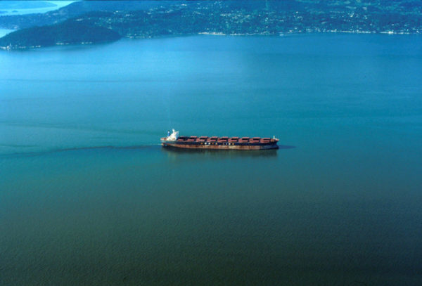 Freight ship of the "Korea Line" clearing its bilge near Vancouver harbour, British Columbia, Canada. Oil slick showing in the ship's wake.