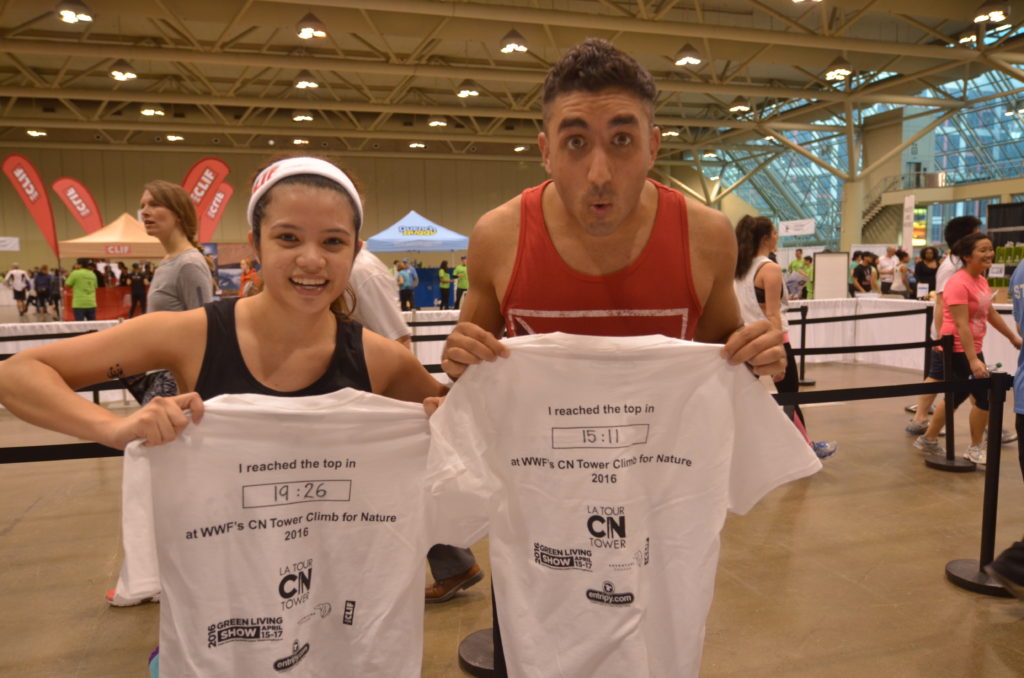 A man and woman showing off the climb times on the back of their T-shirts.