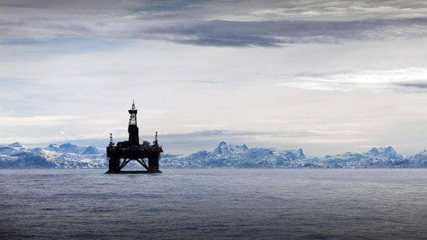 Arctic offshore oil rig with ice-covered mountains in background