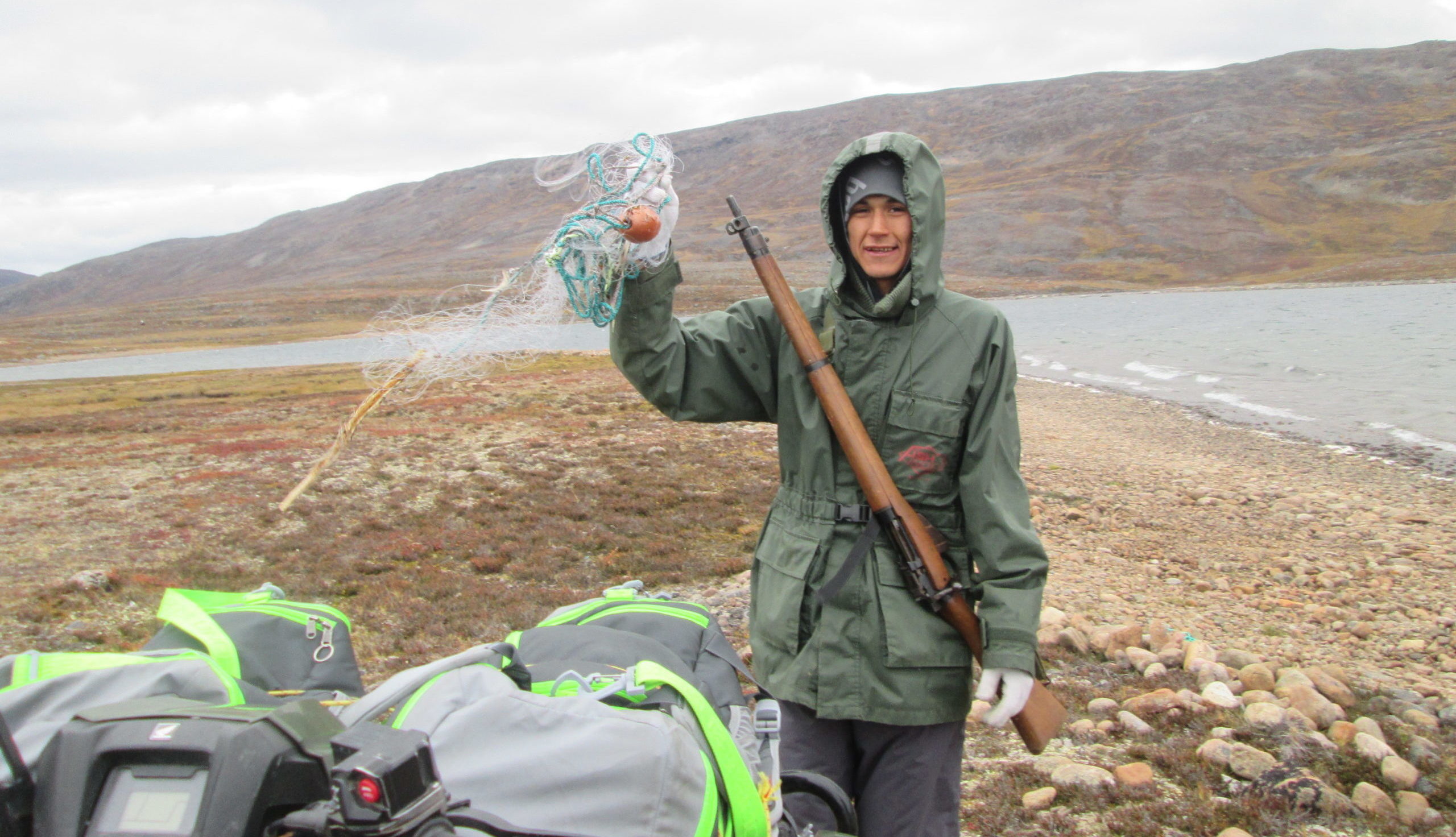Person holds up litter found while doing a shoreline cleanup in Nungarut, Nunavut