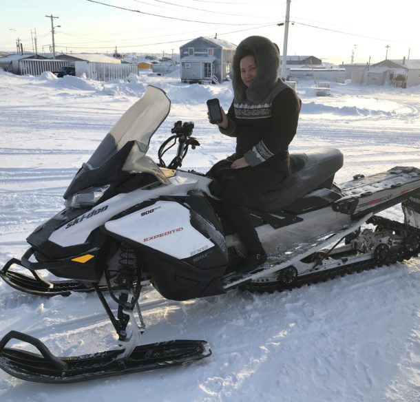 Manager of the polar bear patrol in Whale Cove shows data capturing device while seated on a snowmobile