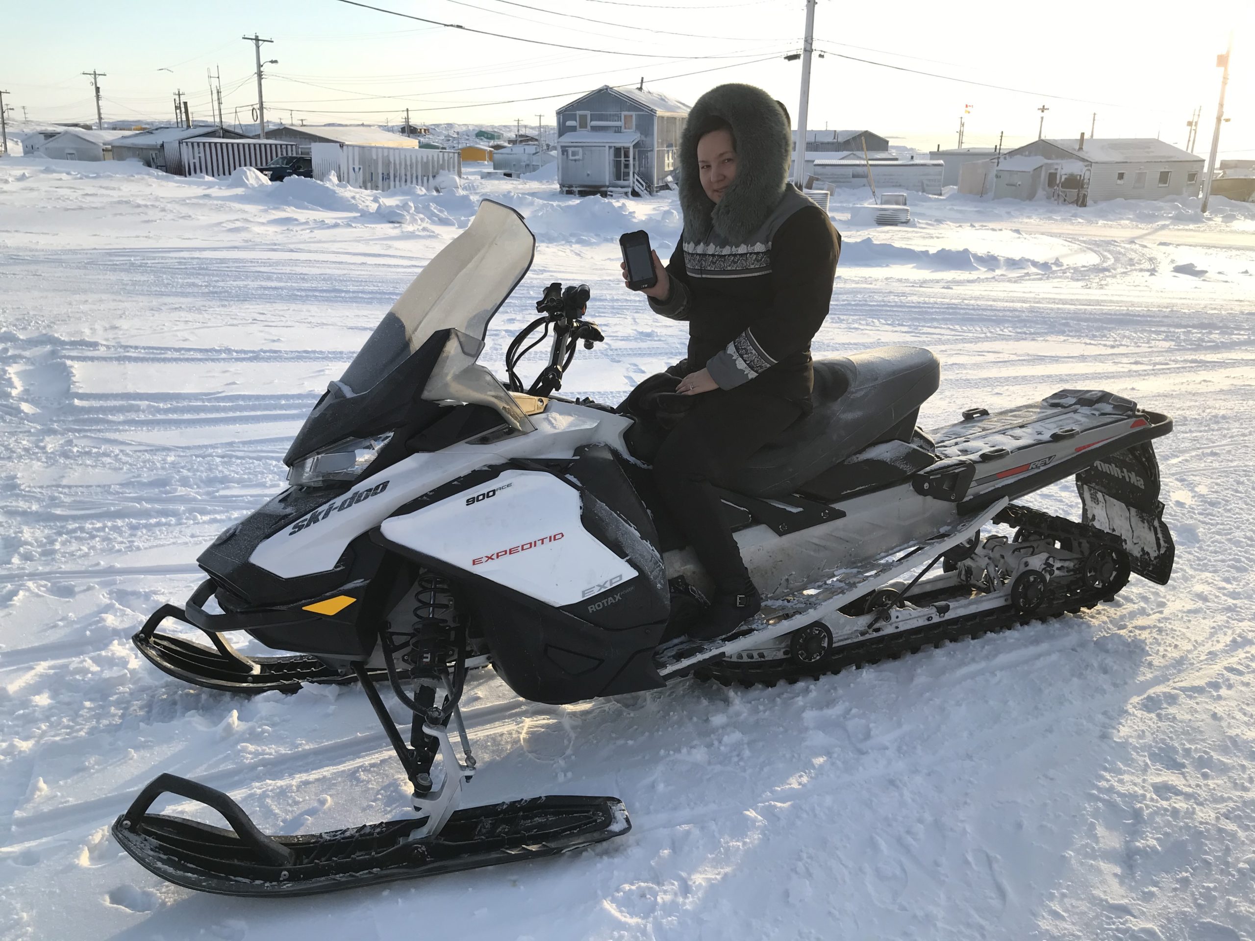 Manager of the polar bear patrol in Whale Cove shows data capturing device while seated on a snowmobile