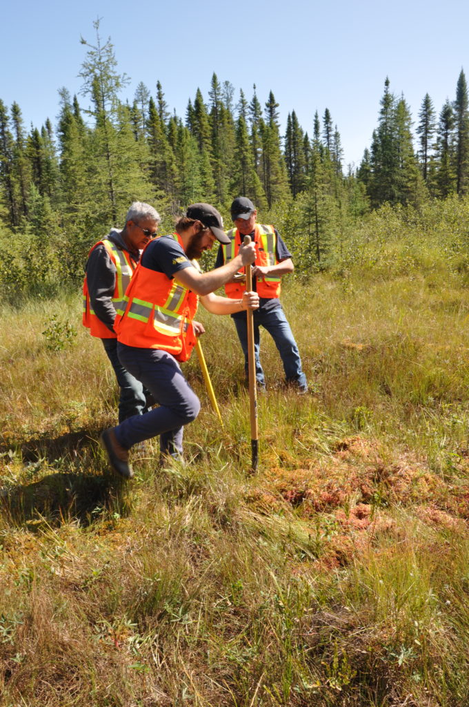 People preparing a sampling site in northern Ontario for peat corers