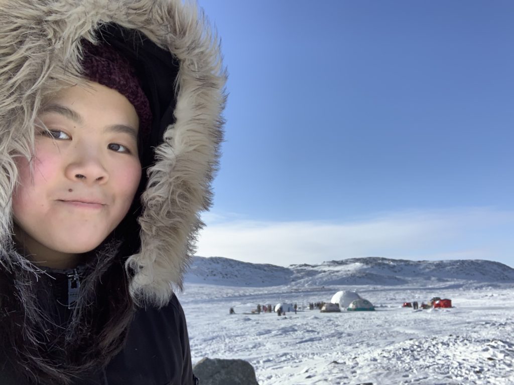 Inuit teen near a qaggiq igloo
