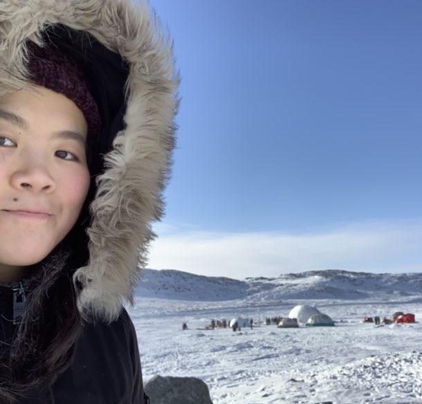 Inuit teen near a qaggiq igloo
