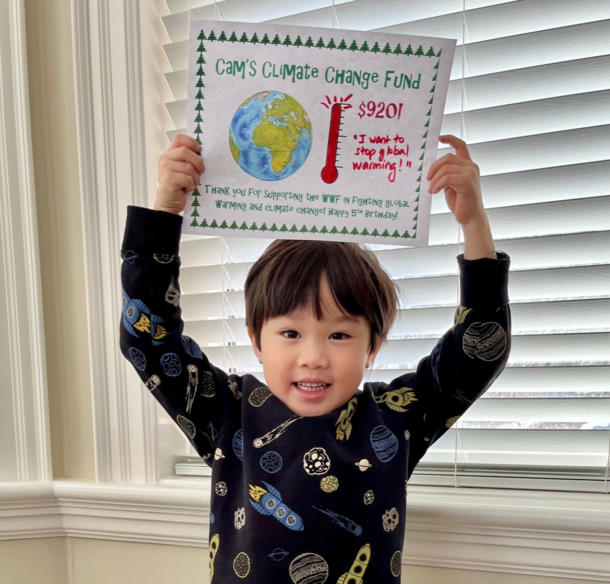 Cameron holding up a picture of the earth and a fundraising thermometer