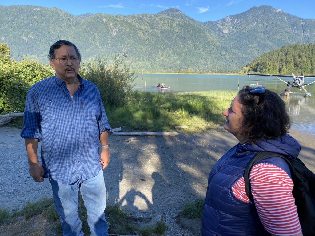 A man from Katzie First Nation and a woman from WWF-Canada talk in the sunshine near a lake