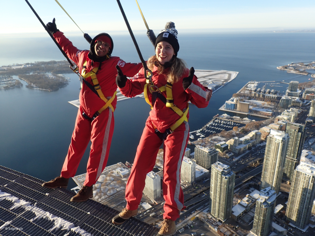 Emily Giles and comedian Jean Paul lean back on the EdgeWalk.