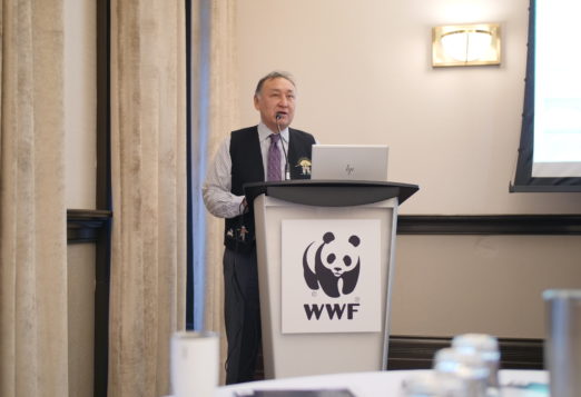 Inuit man standing behind a podium with a WWF panda logo on it