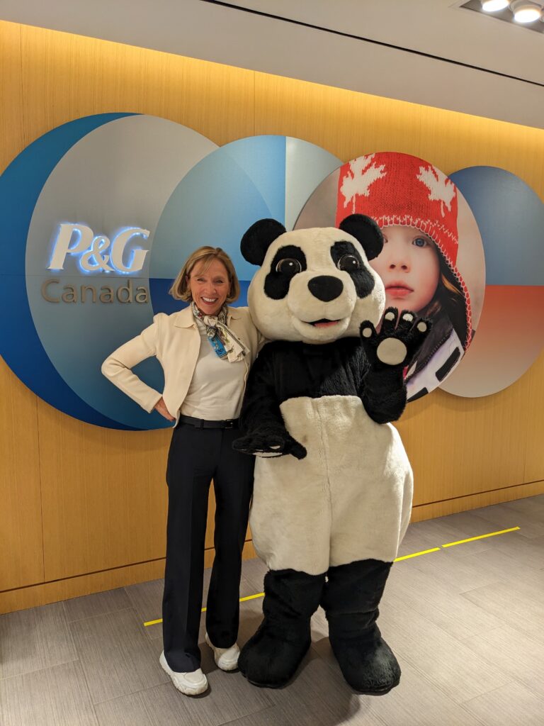 Geraldine Huse, President of P&G Canada, posing with WWF's panda mascot at the P&FG office. 