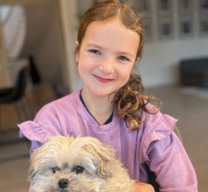 Young girl smiling, holding a dog 