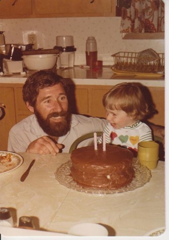 Little girl with bearded dad and birthday cake in the 1970s