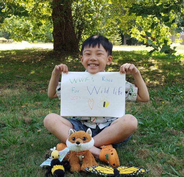 Young boy holds up a handmade "Race for Wildlife" sign