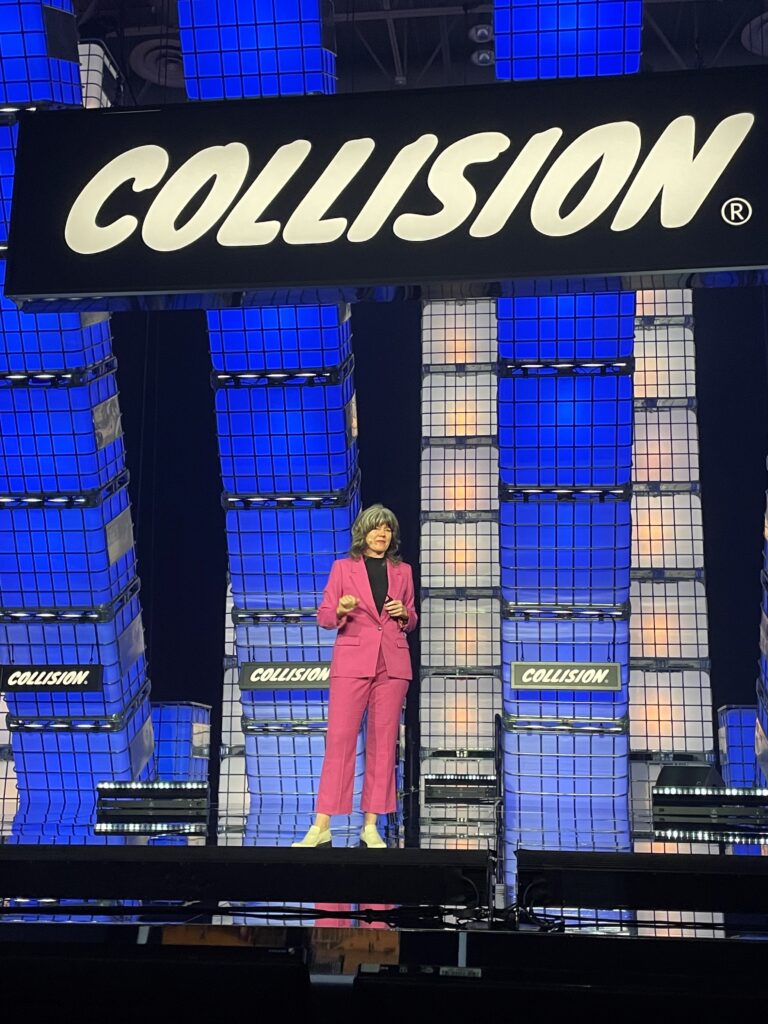 Woman stands on stage that says Collision in the background