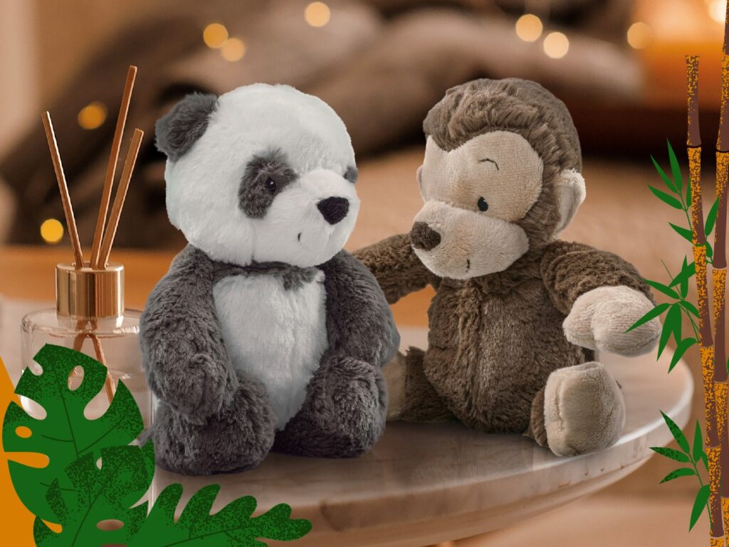 Panu Panda and Mago Monkey plush sit on a table with a holiday backdrop.