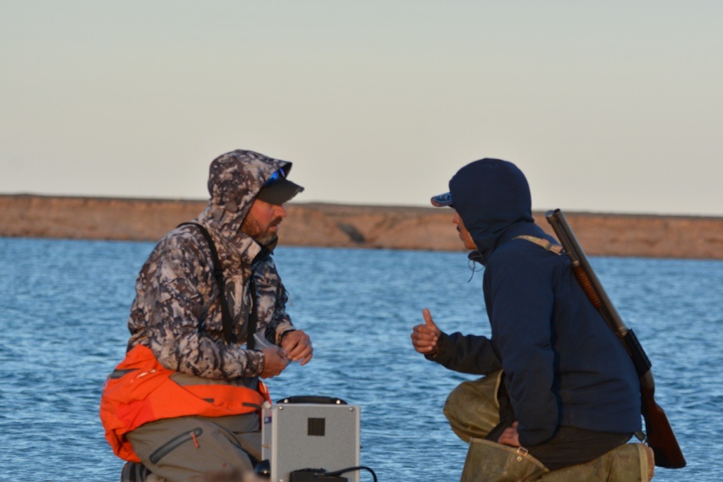 Two men, in front of the Arctic ocean, giving each other thumbs up 