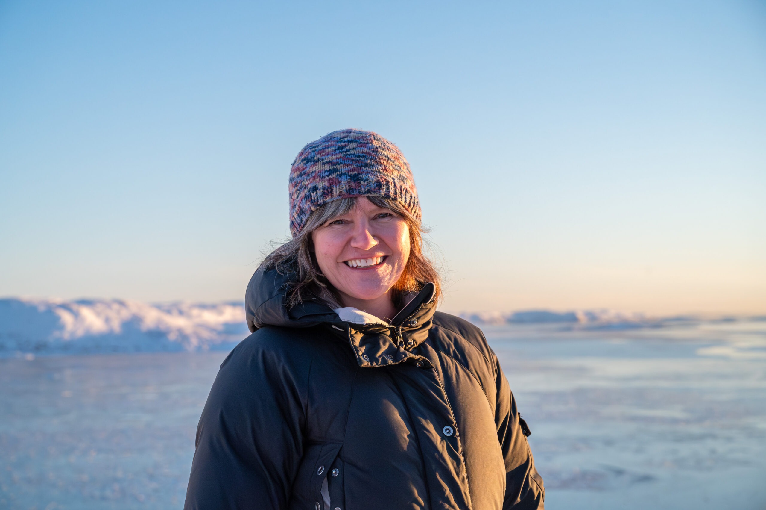 Woman, smiling, in a sunny arctic landscape during winter