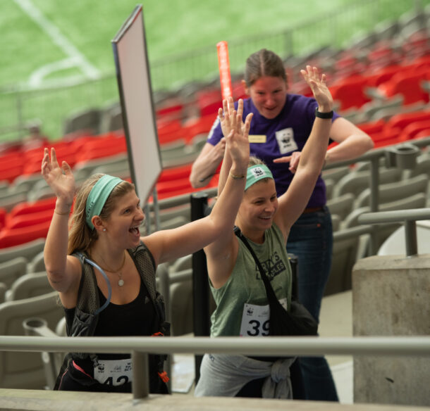 Two women climbing the BC Place stadium stands being cheered on by a WWF-Canada staffer for the Climb for Nature