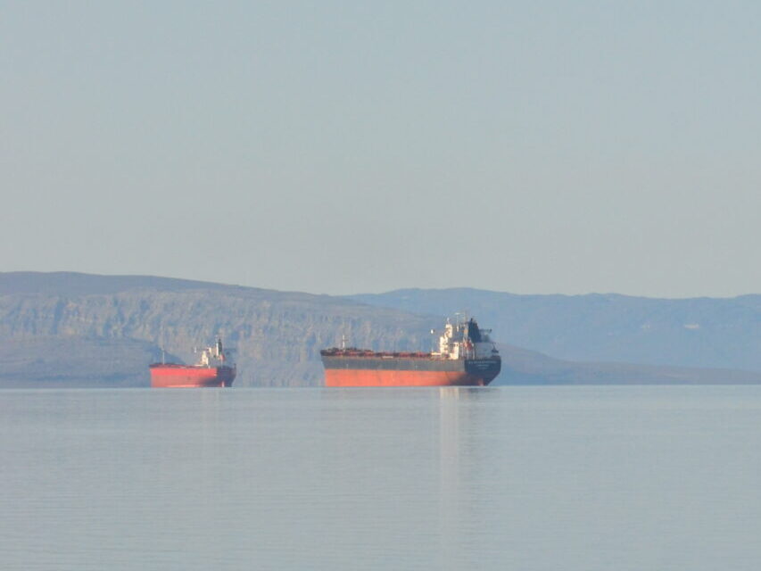 Ore carrier ships in Arctic with land in distant background