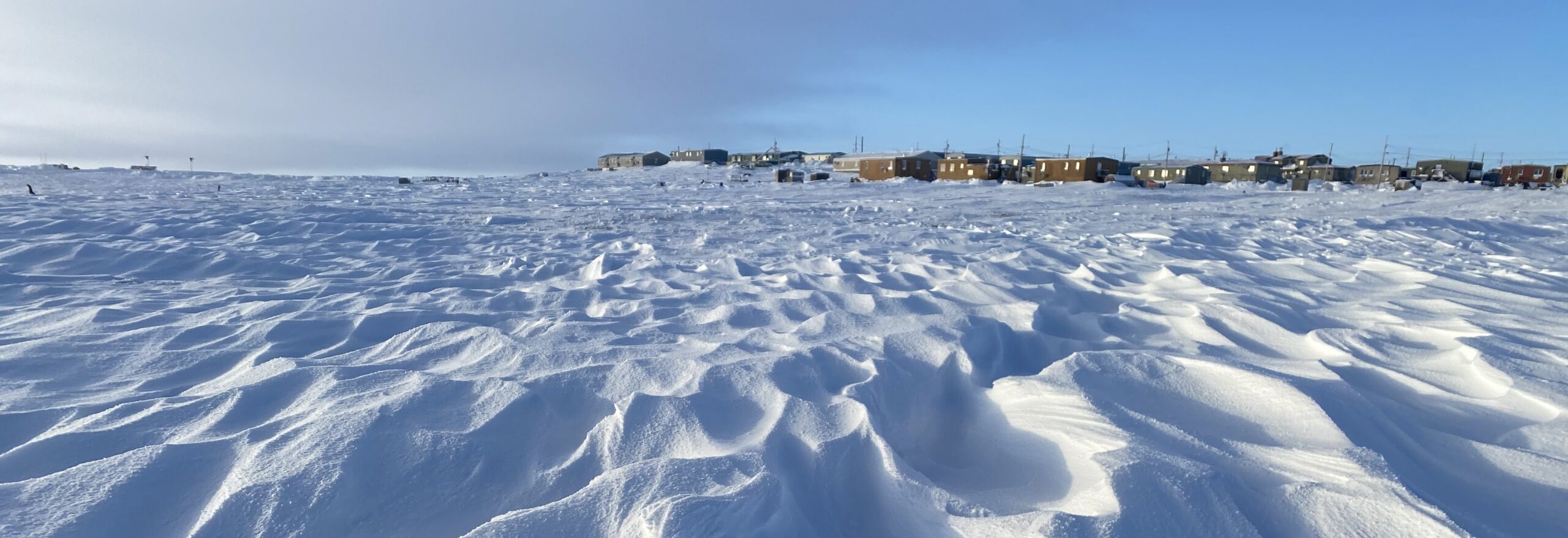 A close-up of a snowfield with a small town on the distant horizon