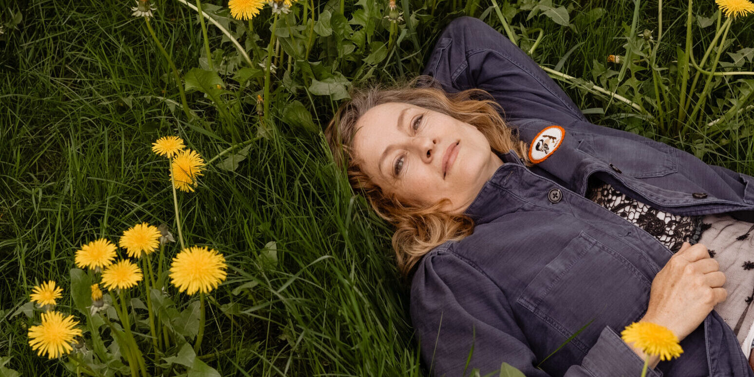 Woman lying in a grass field surrounded by daisies