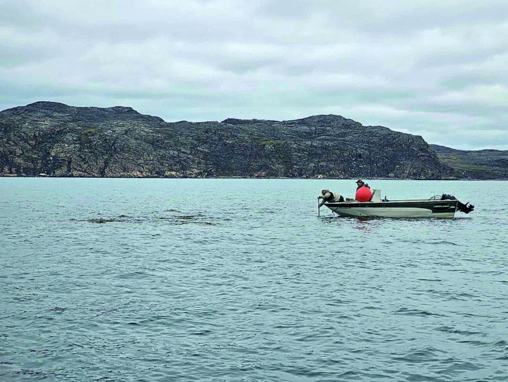 A metal boat on the water with hilly background