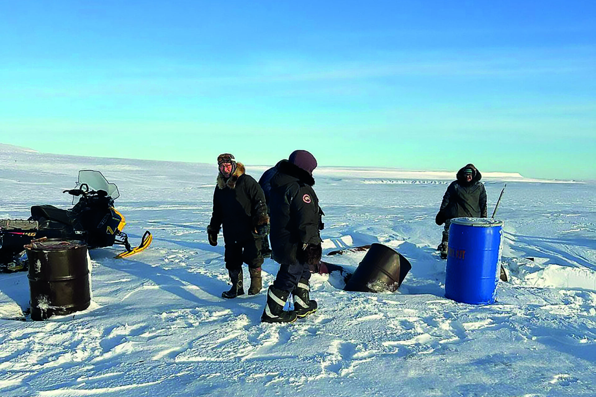 Group of men remove waste barrels left on the Arctic tundra 