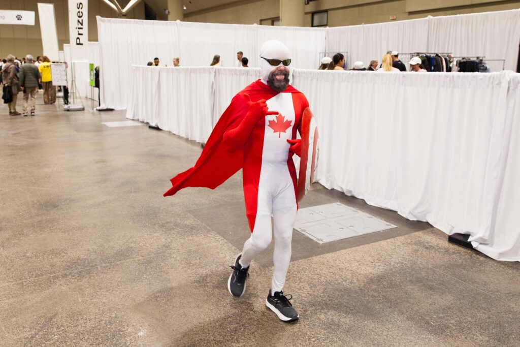 Clifford Redford in a red and white costume with a maple leaf and red cape in the Metro Toronto Convention Centre waiting to climb the CN Tower. 