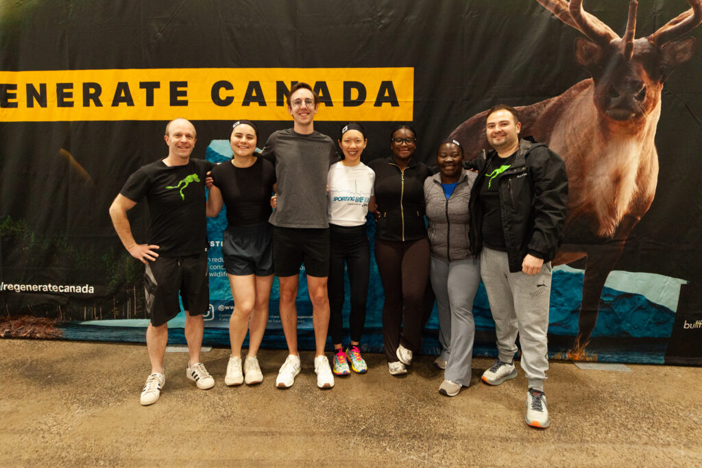a group of people standing in front of a sign that says regenerate canada