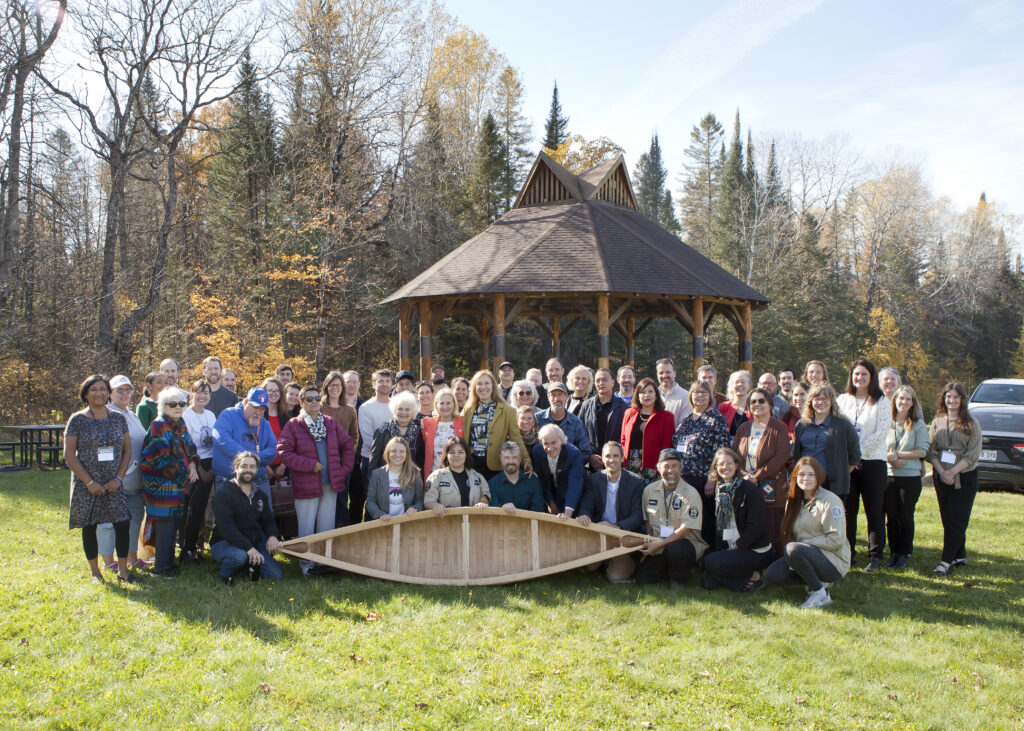 Group photo with canoe near wooden gazebo outdoors