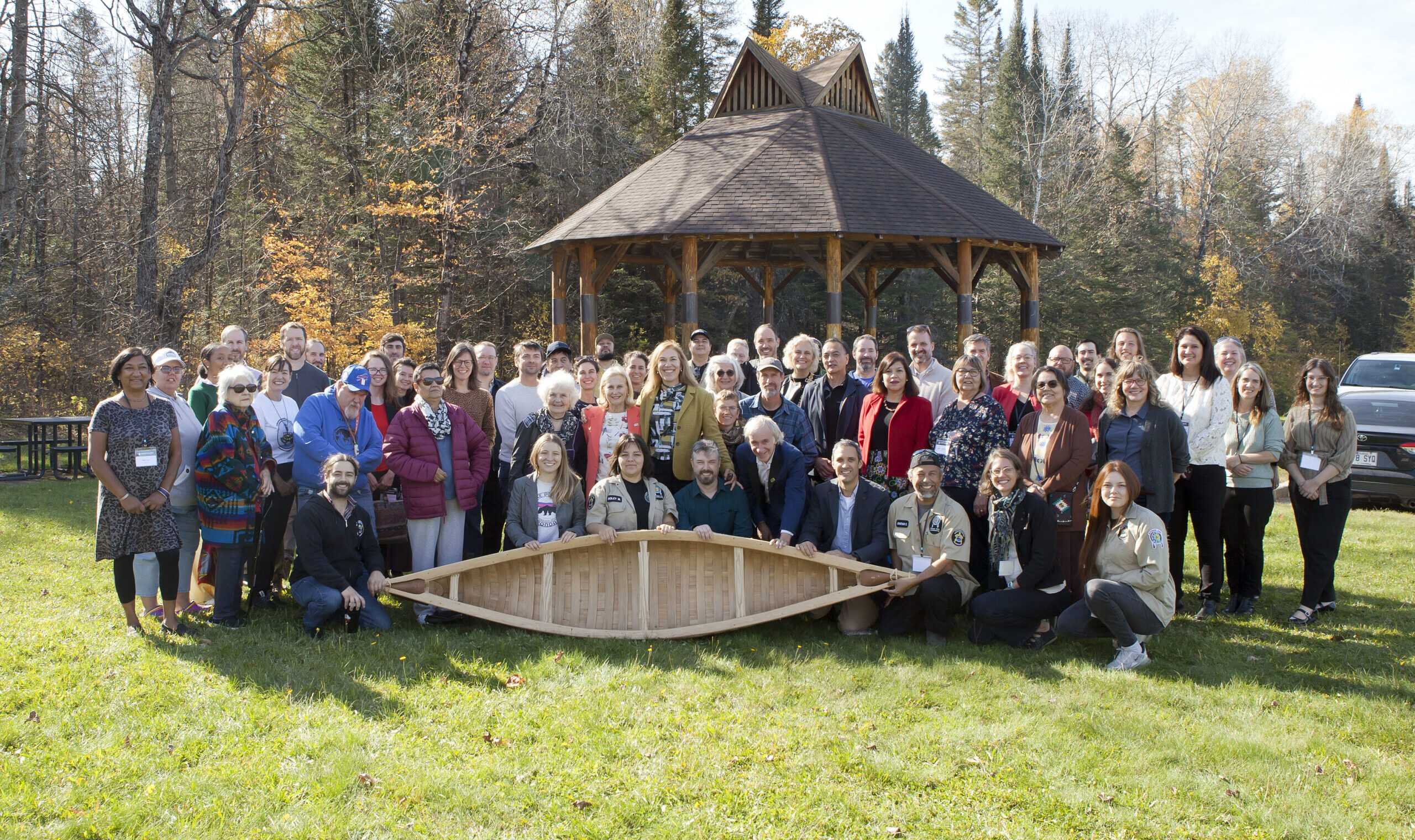 Group photo with canoe near wooden gazebo outdoors